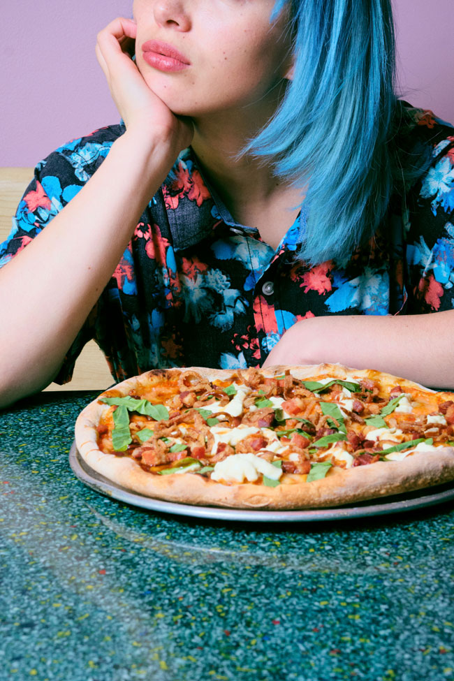 Persona sentada con una pizza en frente